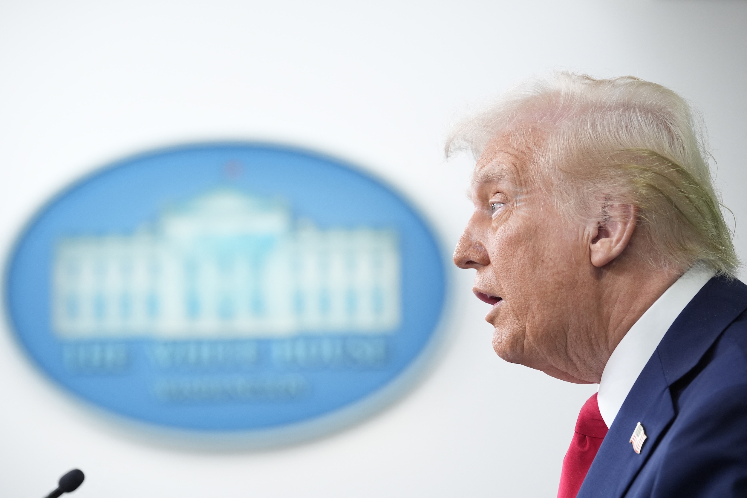 President Donald Trump in front of White House logo in the building's press briefing room.